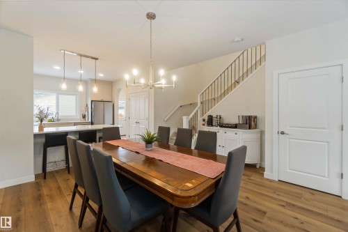 Dining area with light wood-style floors, hanging lights, and arched walkways - 72 Penn Place, Spruce Grove, AB - Indoor Photo Showing Dining Room