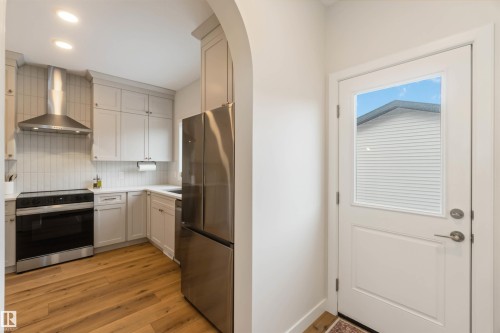Kitchen with range with electric cooktop, freestanding refrigerator, backsplash, light wood finished floors, and white cabinetry - 72 Penn Place, Spruce Grove, AB - Indoor Photo Showing Kitchen