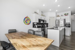 Kitchen with a breakfast bar, stainless steel appliances, white cabinetry, a center island, and dark wood finished floors - 