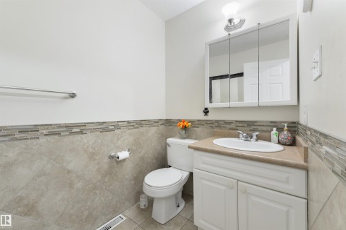 Bathroom with vanity, tile walls, light tile patterned floors, and wainscoting - 11522 128 Street, Edmonton, AB - Indoor Photo Showing Bathroom