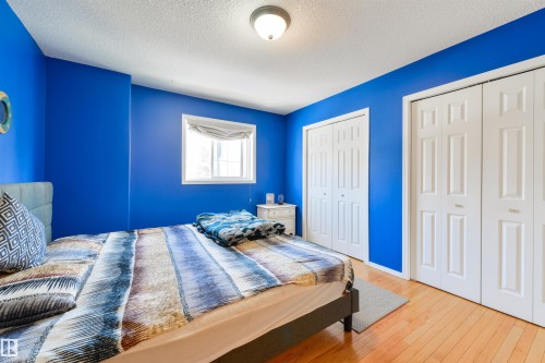 Bedroom featuring two closets, wood-type flooring, and a textured ceiling - 11522 128 Street, Edmonton, AB - Indoor Photo Showing Bedroom