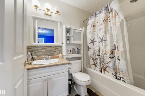 Full bath featuring vanity, shower / bath combo, backsplash, and a textured ceiling - 11522 128 Street, Edmonton, AB - Indoor Photo Showing Bathroom