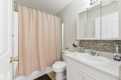 Full bathroom featuring vanity, a textured ceiling, shower / bath combo, backsplash, and tile patterned flooring - 11522 128 Street, Edmonton, AB - Indoor Photo Showing Bathroom