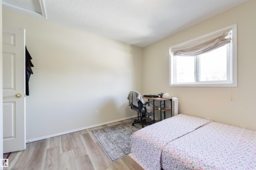 Bedroom with light wood-type flooring, a desk, and a textured ceiling - 11522 128 Street, Edmonton, AB - Indoor Photo Showing Bedroom