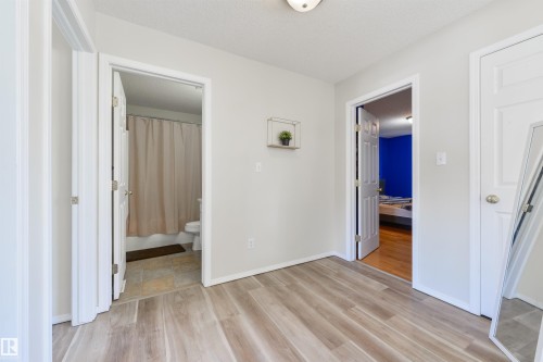 Unfurnished bedroom featuring ensuite bath, light wood-style flooring, and a textured ceiling - 11522 128 Street, Edmonton, AB - Indoor Photo Showing Other Room