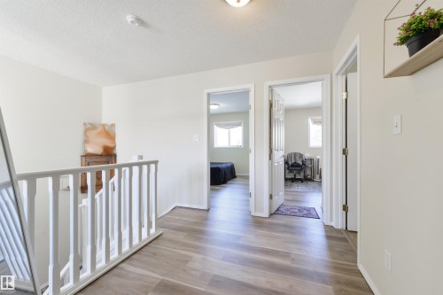 Hallway featuring light wood-style floors, a textured ceiling, and an upstairs landing - 11522 128 Street, Edmonton, AB - Indoor Photo Showing Other Room