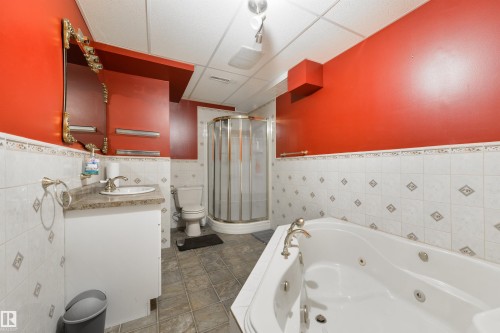 Full bathroom featuring tile walls, a wainscoted wall, vanity, a shower stall, and a tub with jets - 11522 128 Street, Edmonton, AB - Indoor Photo Showing Bathroom