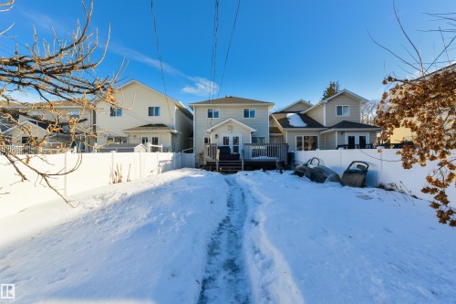 Snow covered back of property with a fenced backyard, a deck, and a residential view - 11522 128 Street, Edmonton, AB - Outdoor