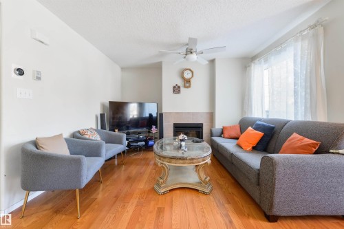 Living area with light wood-type flooring, a fireplace, a ceiling fan, and a textured ceiling - 11522 128 Street, Edmonton, AB - Indoor Photo Showing Living Room With Fireplace