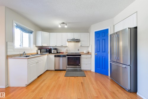Kitchen featuring stainless steel appliances, white cabinetry, light countertops, light wood-type flooring, and tasteful backsplash - 11522 128 Street, Edmonton, AB - Indoor Photo Showing Kitchen With Stainless Steel Kitchen With Double Sink