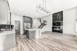 Kitchen featuring gray cabinetry, pendant lighting, a center island with sink, stainless steel refrigerator with ice dispenser, and light wood-type flooring - 