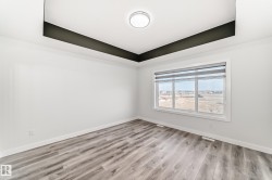 Unfurnished room featuring a tray ceiling and light wood-type flooring - 