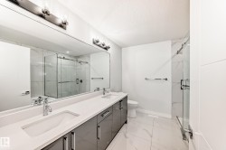 Full bath with a marble finish shower, double vanity, light marble finish flooring, and a textured ceiling - 
