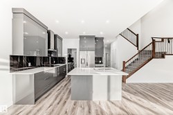 Kitchen with modern cabinets, gray cabinets, stainless steel fridge, an island with sink, and light wood-type flooring - 