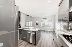 Kitchen with modern cabinets, black electric cooktop, stainless steel dishwasher, pendant lighting, and light wood-style floors - 