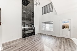 Unfurnished living room with a high ceiling, light wood-type flooring, and a chandelier - 