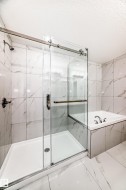Full bath with a bath, a marble finish shower, marble look tile flooring, and a textured ceiling - 