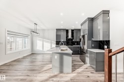 Kitchen with gray cabinets, decorative light fixtures, modern cabinets, decorative backsplash, and stainless steel fridge - 