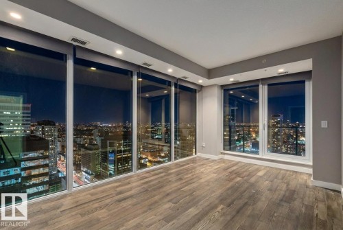 Empty room with a view of city lights, wood finished floors, and recessed lighting - 3300 10180 103 Street, Edmonton, AB - Indoor Photo Showing Other Room
