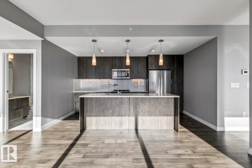 Kitchen with modern cabinets, stainless steel appliances, a kitchen island with sink, and pendant lighting - 3300 10180 103 Street, Edmonton, AB - Indoor Photo Showing Kitchen With Stainless Steel Kitchen With Upgraded Kitchen
