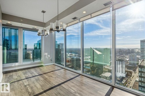 Empty room featuring a city view, light wood-style floors, suspended lighting, and plenty of natural light - 3300 10180 103 Street, Edmonton, AB - Indoor Photo Showing Other Room