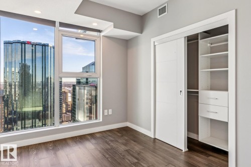 Unfurnished bedroom featuring dark wood finished floors, a closet, and a view of city - 3300 10180 103 Street, Edmonton, AB - Indoor Photo Showing Other Room