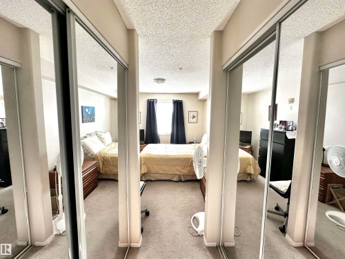 Bedroom featuring multiple closets, a textured ceiling, and light colored carpet - 215 13625 34 Street, Edmonton, AB - Indoor Photo Showing Bedroom