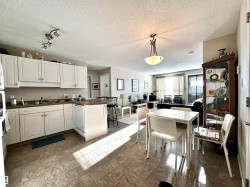 Kitchen featuring dark countertops, a peninsula, decorative light fixtures, white cabinets, and a textured ceiling - 