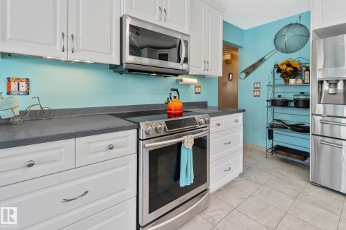 Kitchen with dark countertops, white cabinets, stainless steel appliances, and light tile patterned floors - 4231 39 Avenue, Leduc, AB - Indoor Photo Showing Kitchen