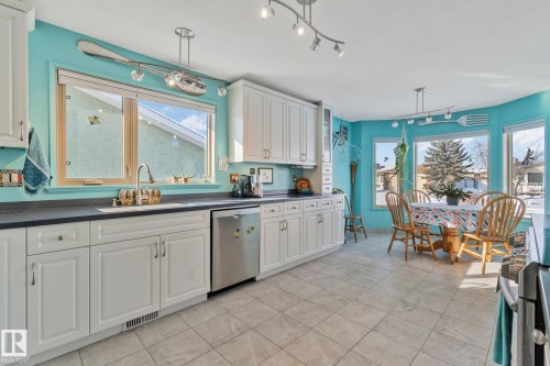 Kitchen with dark countertops, white cabinetry, stainless steel appliances, and rail lighting - 4231 39 Avenue, Leduc, AB - Indoor Photo Showing Kitchen