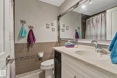 Bathroom with vanity, a shower with shower curtain, tile walls, light tile patterned floors, and a wainscoted wall - 4231 39 Avenue, Leduc, AB - Indoor Photo Showing Bathroom