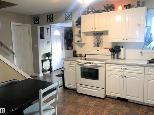 Kitchen featuring white cabinetry, white electric stove, light countertops, and open shelves - 4735 48 Ave, Evansburg, AB - Indoor Photo Showing Kitchen