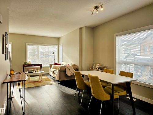 Dining room featuring dark wood-style flooring and a textured ceiling - 129 2560 Pegasus Boulevard, Edmonton, AB - Indoor