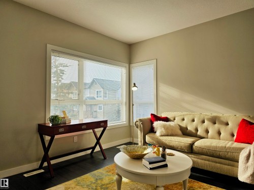 Living area featuring dark wood-style flooring and baseboards - 129 2560 Pegasus Boulevard, Edmonton, AB - Indoor Photo Showing Other Room