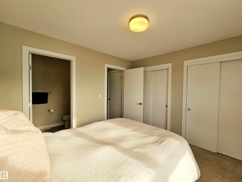 Bedroom featuring multiple closets, carpet, and ensuite bathroom - 129 2560 Pegasus Boulevard, Edmonton, AB - Indoor Photo Showing Bedroom