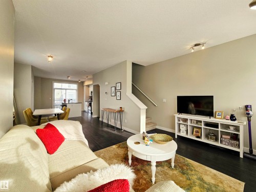 Living area with stairs and wood finished floors - 129 2560 Pegasus Boulevard, Edmonton, AB - Indoor Photo Showing Living Room
