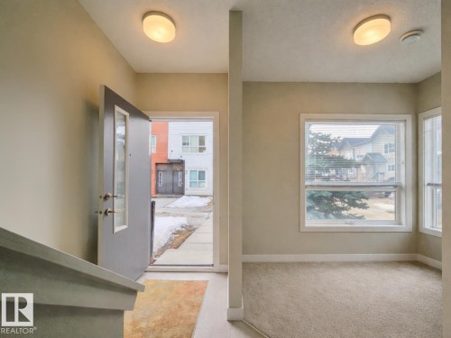Foyer featuring baseboards and light tile patterned floors - 129 2560 Pegasus Boulevard, Edmonton, AB - Indoor Photo Showing Other Room