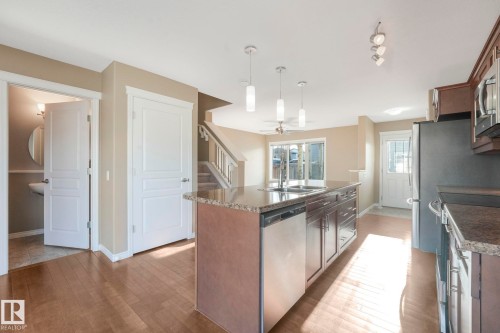 Kitchen with stainless steel appliances, decorative light fixtures, an island with sink, a ceiling fan, and dark countertops - 385 Secord Boulevard, Edmonton, AB - Indoor Photo Showing Kitchen With Double Sink With Upgraded Kitchen
