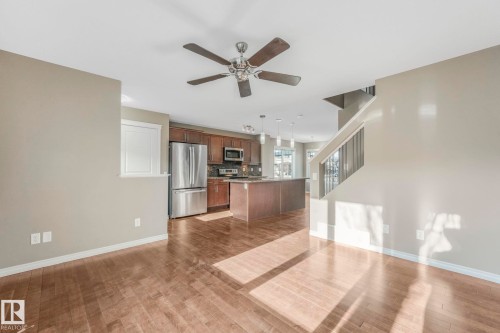 Kitchen with open floor plan, stainless steel appliances, a ceiling fan, hanging light fixtures, and dark wood-style floors - 385 Secord Boulevard, Edmonton, AB - Indoor Photo Showing Kitchen