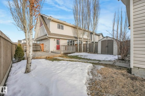 Snow covered rear of property featuring a fenced backyard, a deck, roof with shingles, and a shed - 385 Secord Boulevard, Edmonton, AB - Outdoor With Deck Patio Veranda