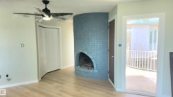 Unfurnished living room featuring wood finished floors, a brick fireplace, and a ceiling fan - 