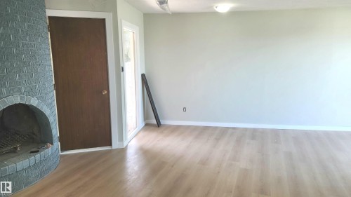 Unfurnished living room with a fireplace and light wood finished floors - 9535 147 Avenue, Edmonton, AB - Indoor Photo Showing Other Room With Fireplace