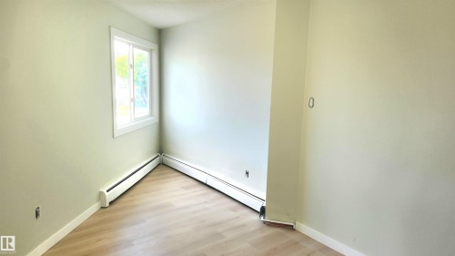 Spare room featuring light wood-type flooring, a baseboard radiator, and a textured ceiling - 9535 147 Avenue, Edmonton, AB - Indoor Photo Showing Other Room