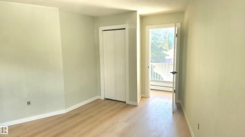 Unfurnished bedroom featuring light wood-style flooring, a closet, a baseboard heating unit, and a textured ceiling - 9535 147 Avenue, Edmonton, AB - Indoor Photo Showing Other Room