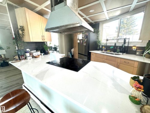 Kitchen with light brown cabinetry, tasteful backsplash, and light stone countertops - 9535 147 Avenue, Edmonton, AB - Indoor