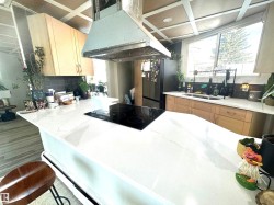 Kitchen with light brown cabinetry, tasteful backsplash, and light stone countertops - 