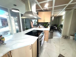 Kitchen featuring light brown cabinets, stainless steel electric stove, light stone countertops, and island range hood - 