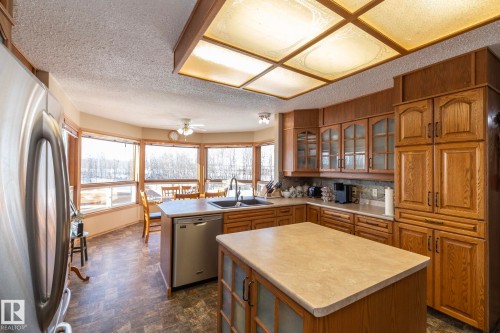 Kitchen with wood finish cabinetry, stainless steel appliances, glass insert cabinets and a kitchen island - 57524 Range Road 270, Rural Westlock County, AB - Indoor Photo Showing Kitchen With Double Sink