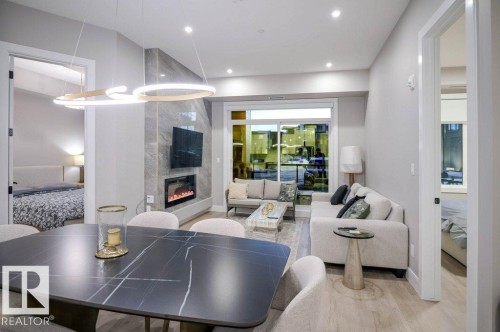 Living area with wood finished floors, a premium fireplace, and recessed lighting - 101 7471 May Common, Edmonton, AB - Indoor With Fireplace