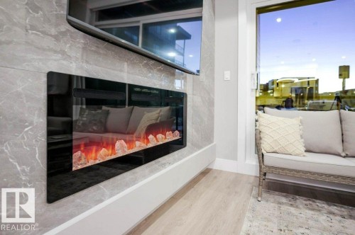 Detailed view of wood finished floors and a glass covered fireplace - 101 7471 May Common, Edmonton, AB - Indoor Photo Showing Living Room With Fireplace